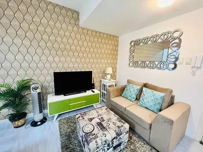 a living room with a couch and a tv at Azure 2bedroom Condo With Balcony in Manila