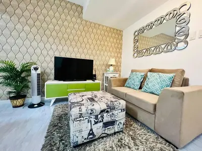 a living room with a couch and a tv at Azure 2bedroom Condo With Balcony in Manila