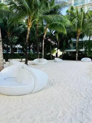 a beach with chairs and palm trees and a building at Scr AzureINetflixIBalconyIGames in Manila
