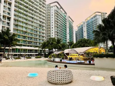 two people sitting on the beach in a resort at Scr AzureINetflixIBalconyIGames in Manila