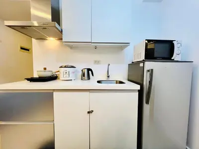 a small kitchen with a microwave and a refrigerator at Scr GlamourINetFlixIBalconyICozy in Manila