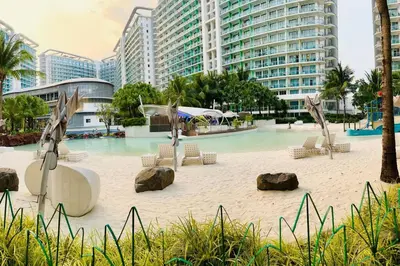a beach with chairs and rocks and buildings at Scr GlamourINetFlixIBalconyICozy in Manila