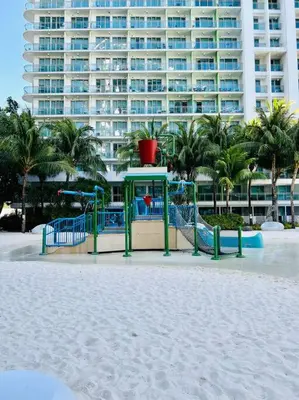 a playground on the beach in front of a large building at Scr GlamourINetFlixIBalconyICozy in Manila