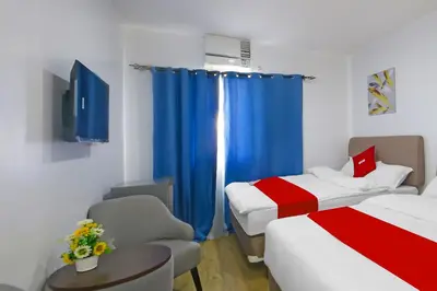 a room with two beds and a window with blue curtains at Loveness Apartelle in Manila