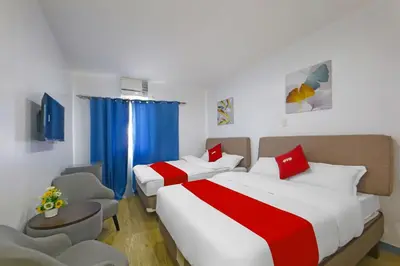 two beds in a hotel room with blue curtains at Loveness Apartelle in Manila