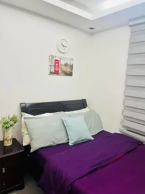 a bedroom with a bed with purple sheets and a clock on the wall at ADB Tower 1 bedroom with fast wifi and Netflix at Ortigas across Robinson's Galleria in Manila
