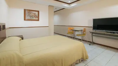 a bedroom with a bed and a flat screen tv at Garden Plaza Hotel Manila in Manila