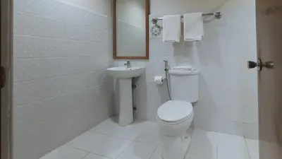 a bathroom with a toilet and a sink at Garden Plaza Hotel Manila in Manila