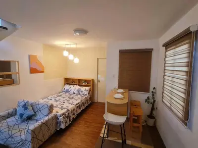 a bedroom with a bed and a table and a chair at Muji-Inspired, Studio-Type Home at Phirst Park Homes Tanza in Tanza
