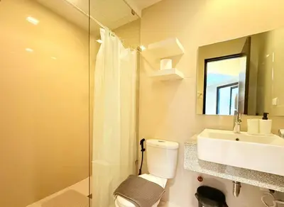 a bathroom with a toilet and a sink and a mirror at Uptown Parksuites BGC in Manila