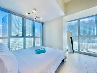 a bedroom with a large white bed with large windows at Uptown Parksuites BGC in Manila