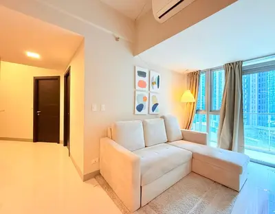a living room with a white couch and a large window at Uptown Parksuites BGC in Manila