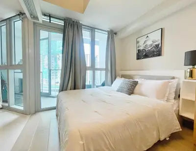 a bedroom with a large white bed and glass doors at Uptown Parksuites BGC in Manila