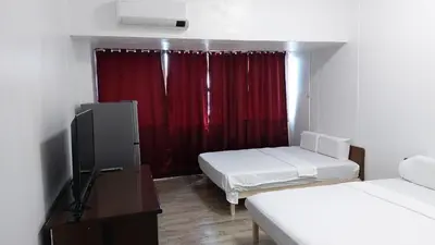 a room with two beds and a television and a red curtain at MANILA BAY EXECUTIVE SUITE pearl of orient in Manila