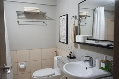 a bathroom with a sink and a toilet and a mirror at Alea Residences in Manila