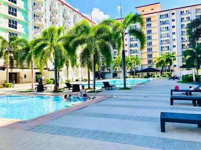a swimming pool with palm trees and people in it at Field Residence SMDC 1BR w/ Netflix in Manila