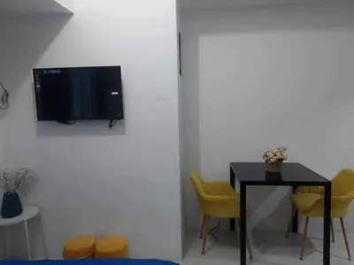 a room with a table and a tv on a wall at Cozy Condo near US EmbassyErmita Manila/ Roxas blvd/ Dolomite beach in Manila