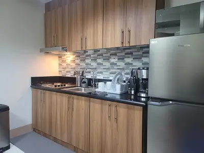 a kitchen with wooden cabinets and a stainless steel refrigerator at A&R Condo by the Bay in Manila