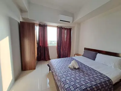 a bedroom with a bed with a plaid blanket and a window at Elresa Elegant at Field Residences Condominium Hotel in Manila