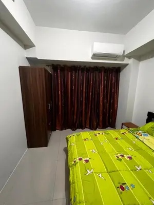 a bedroom with a green bed and a window at Elresa Elegant at Field Residences Condominium Hotel in Manila