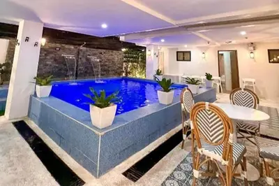 a swimming pool in a house with a table and chairs at Aurora Suites Pasay near Airport in Manila