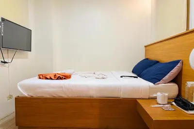 a bedroom with a bed with a desk and a television at Aurora Suites Pasay near Airport in Manila
