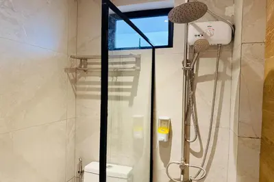a shower stall in a bathroom with a toilet at Aurora Suites Pasay near Airport in Manila