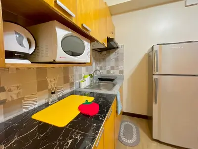 a small kitchen with a sink and a refrigerator at Rafaella Sunset - Deluxe Room in Manila