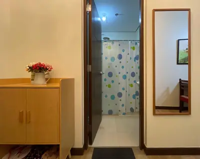 a bathroom with a shower and a dresser with a mirror at Rafaella Sunset - Deluxe Room in Manila