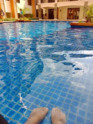 a person laying on the edge of a swimming pool at Rafaella Sunset - Deluxe Room in Manila