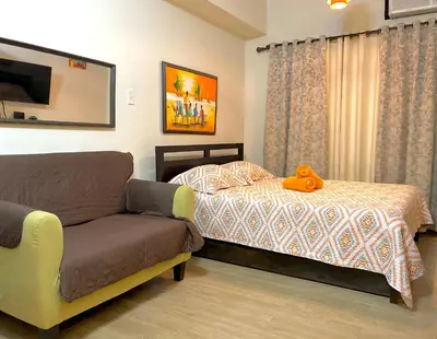 a bedroom with a bed and a couch with a stuffed animal on it at Rafaella Sunset - Deluxe Room in Manila