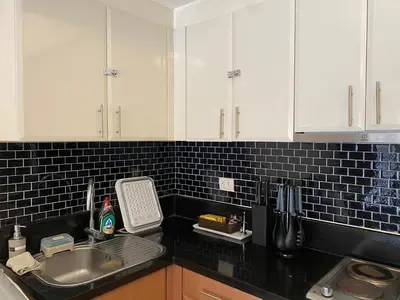 a kitchen with white cabinets and a sink at Spacious condo in Venice Luxury Residences in Manila