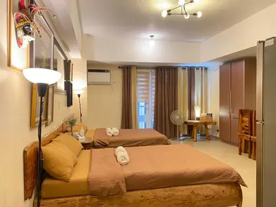 a hotel room with two beds and a desk at Spacious condo in Venice Luxury Residences in Manila