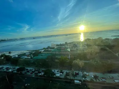a view of a resort with the sun setting over the water at Pearl Of The Orient Tower, in front of US Embassy in Manila