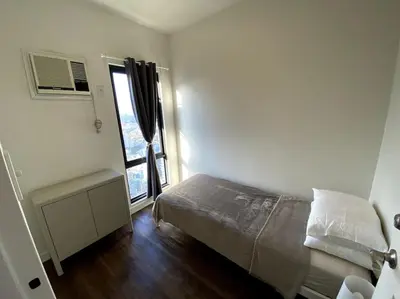 a small bedroom with a bed and a window at Modern Condo Apt in Flair Tower South, Mandaluyong in Manila