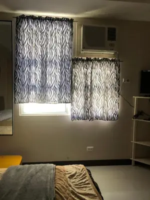 a bedroom with black and white curtains and a window at 101 Newport Boulevard-Favila Condotel Unit near Airport in Manila