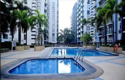 a large swimming pool with palm trees and buildings at KENN PROPERTY in Manila