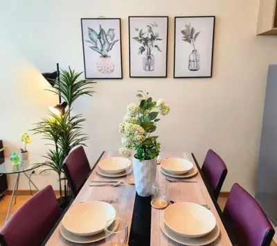 a dining room table with plates and flowers on it at BGC Fresh & Cozy Studio near Burgos Circle with Fast Internet Connection in Manila
