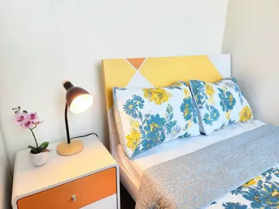 a bed with a lamp on a nightstand next to a bed at BGC Fresh & Cozy Studio near Burgos Circle with Fast Internet Connection in Manila