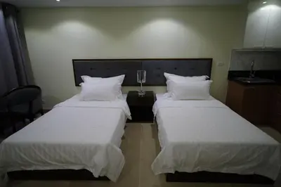 two beds in a hotel room with white sheets and pillows at Luxe in Venice in Manila