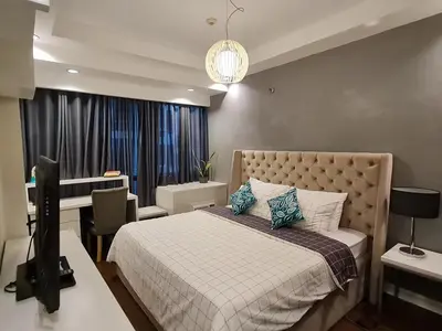 a bedroom with a bed and a desk with a computer at Huge condo unit near Burgos Circle, St Lukes, Shangri-La - P Hamptons T1 in Manila
