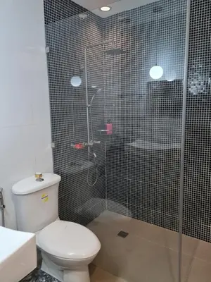 a bathroom with a toilet and a glass shower at Huge condo unit near Burgos Circle, St Lukes, Shangri-La - P Hamptons T1 in Manila
