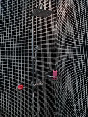 a shower in a bathroom with a black tiled wall at Huge condo unit near Burgos Circle, St Lukes, Shangri-La - P Hamptons T1 in Manila