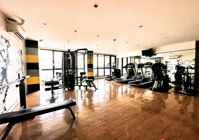 a gym with treadmills and machines in a room at KL Tower Makati near Greenbelt with free access to gym, sauna & 100Mbps Wi-fi in Manila