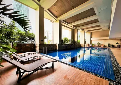 a pool in a building with two chairs next to it at KL Tower Makati near Greenbelt with free access to gym, sauna & 100Mbps Wi-fi in Manila