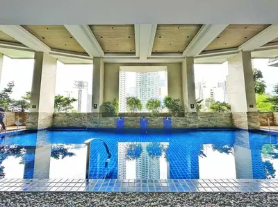 a swimming pool in a building with blue water at KL Tower Makati near Greenbelt with free access to gym, sauna & 100Mbps Wi-fi in Manila