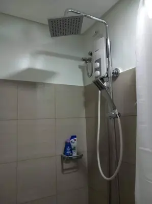 a shower with a shower head in a bathroom at Shore 2 Condo unit near MOA in Manila