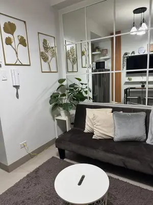 a living room with a black couch and a table at Shore 2 Condo unit near MOA in Manila