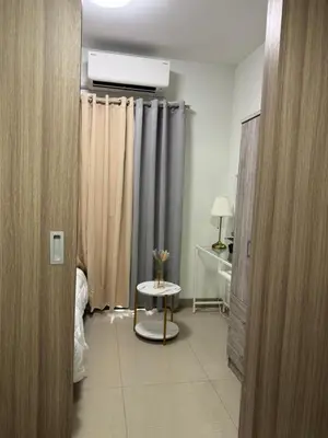a room with a bed and a table and curtains at Shore 2 Condo unit near MOA in Manila