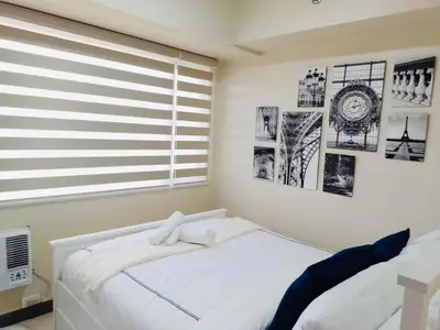 a bedroom with a white bed and a window at Larue cozy room in Solemare Parksuites Paranaque in Manila